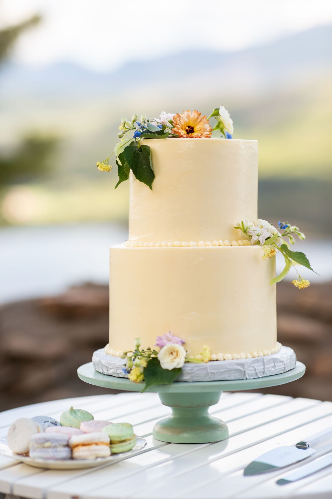 Two-tier pale yellow cake decorated with fresh wildflowers