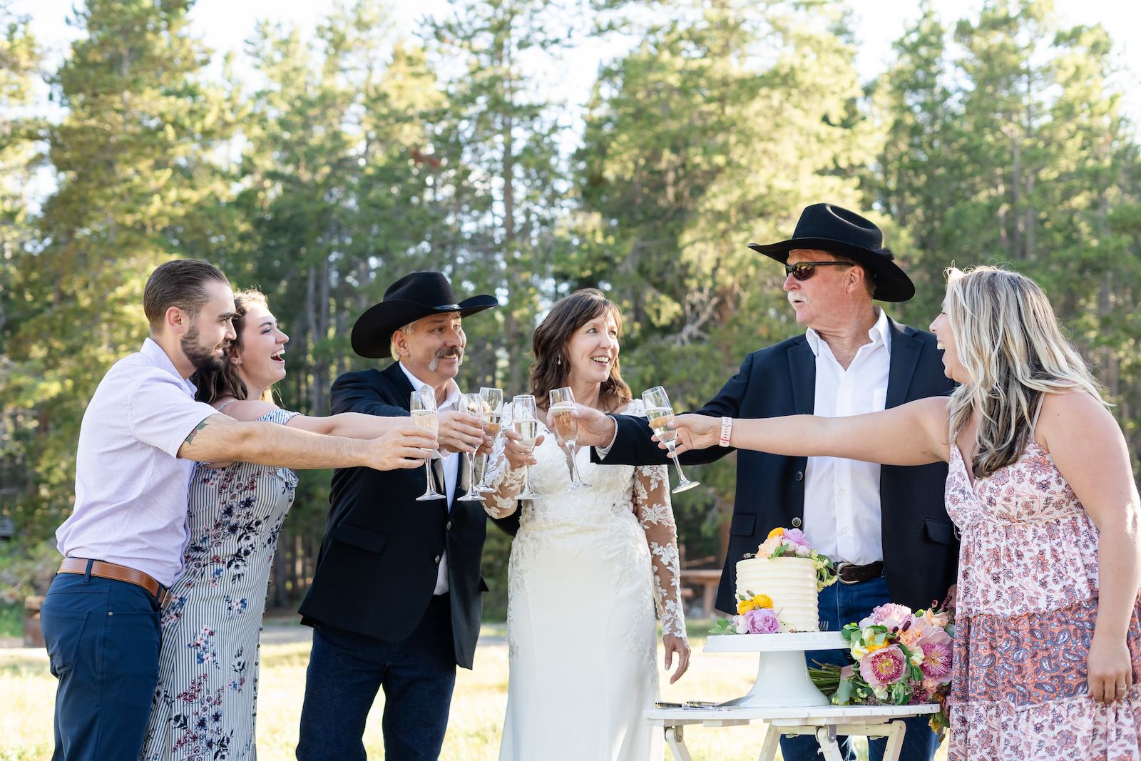 Wedding party toasting with champagne beside a floral cake