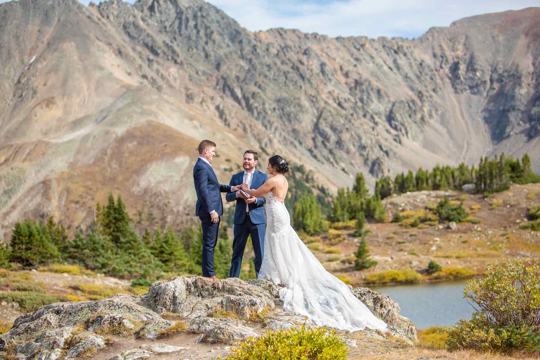 Couple exchanging vows on a rocky ridge above an alpine lake