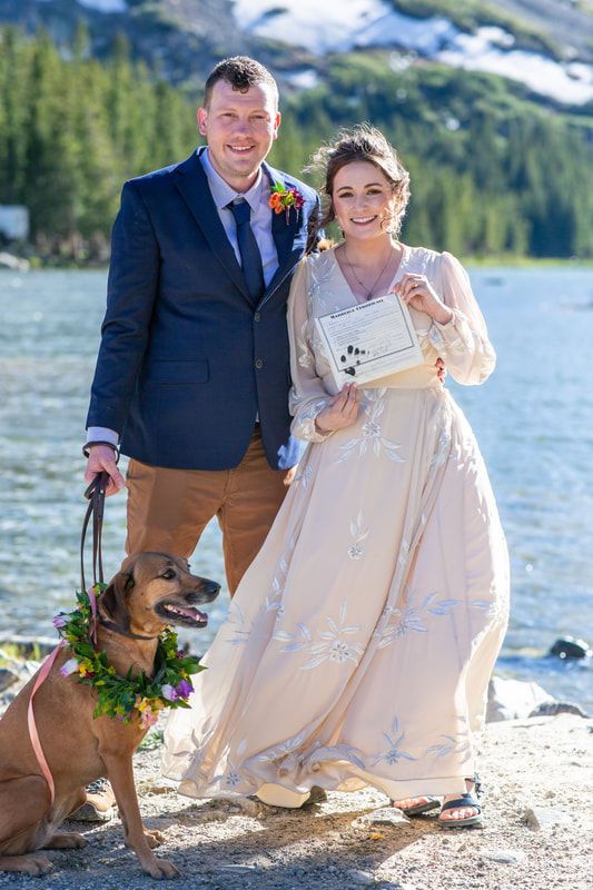 A dog next to a couple signing their Colorado marriage license.